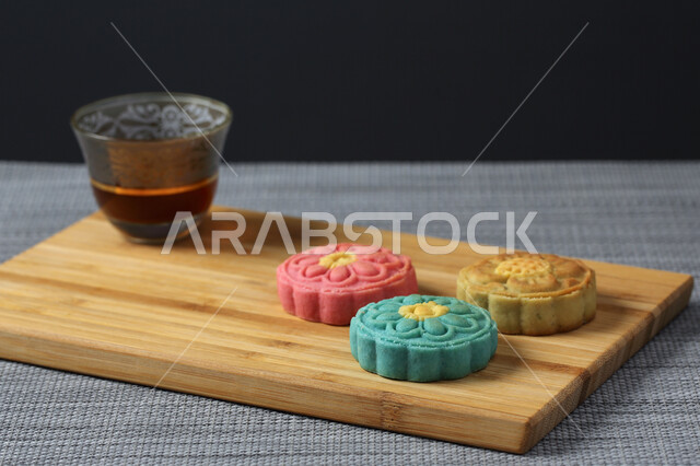 معمول التمر ملون مربع الشكل ، الحلويات الشعبية الهشة على لوح خشبي ، كعك العيد , قهوة عربية ، الضيافة و الاستقبال