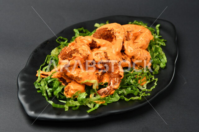 طبق روبيان مع الصوص على سطح أسود ، مطابخ ومطاعم عربية ، الجمبري ، مأكولات بحرية