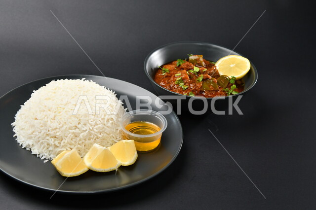 White rice dish with lemon slices and edamame chicken dish on a black surface, Arabic food, Saudi restaurant, Gulf dishes, Saudi kitchen