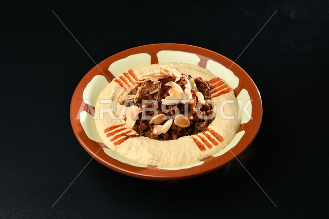 وصفات طعام شرقية عربية سعودية, المقبلات النباتية الباردة اللذيذة، طبق من كريم الحمص المزين بالتوابل والبقدونس مع زيت الزيتون على طاولة سفرة رخامية، مأكولات وأطباق شعبية تقليدية،