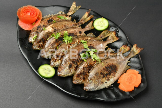 طبق من السمك المقلي المتبل على سطح أسود ، مأكولات بحرية ، مأكولات عربية ، وجبة طعام غذائية صحية ، صيادية سمك