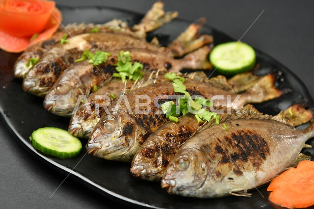 طبق من السمك المقلي المتبل على سطح أسود ، مأكولات بحرية ، مأكولات عربية ، وجبة طعام غذائية صحية ، صيادية سمك