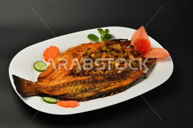 طبق من السمك المقلي المتبل على سطح أسود ، مأكولات بحرية ، مأكولات عربية ، وجبة طعام غذائية صحية ، صيادية سمك