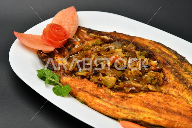 طبق من السمك المقلي المتبل على سطح أسود ، مأكولات بحرية ، مأكولات عربية ، وجبة طعام غذائية صحية ، صيادية سمك