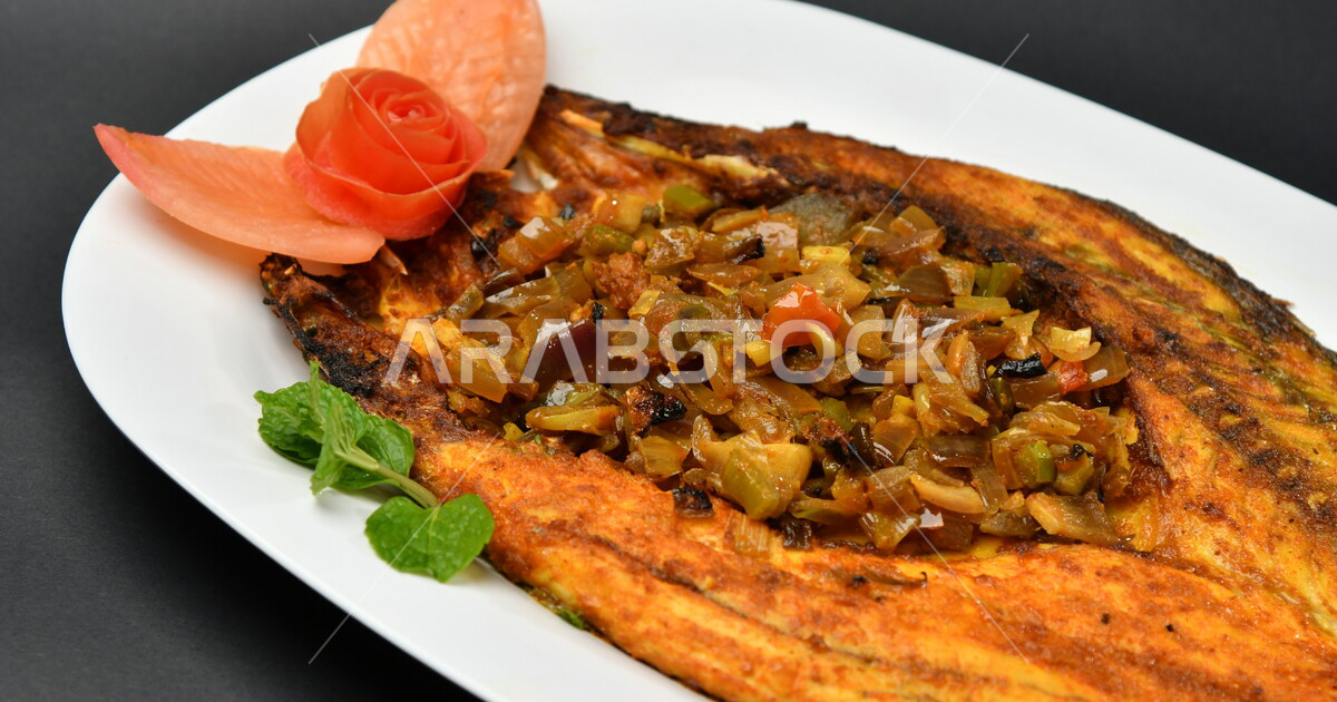 A plate of marinated fried fish on a blackened surface, seafood, arabic