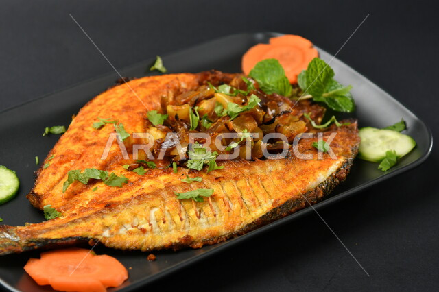 طبق من السمك المقلي المتبل على سطح أسود ، مأكولات بحرية ، مأكولات عربية ، وجبة طعام غذائية صحية ، صيادية سمك