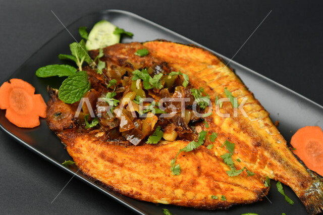 طبق من السمك المقلي المتبل على سطح أسود ، مأكولات بحرية ، مأكولات عربية ، وجبة طعام غذائية صحية ، صيادية سمك