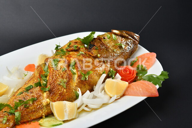 طبق من السمك المقلي المتبل على سطح أسود ، مأكولات بحرية ، مأكولات عربية ، وجبة طعام غذائية صحية ، صيادية سمك