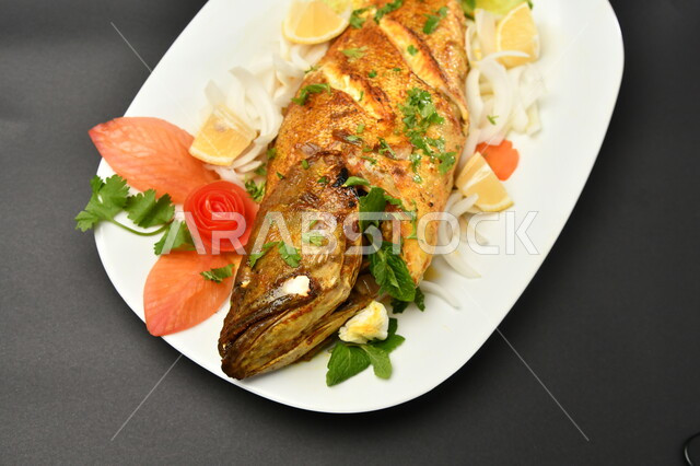طبق من السمك المقلي المتبل على سطح أسود ، مأكولات بحرية ، مأكولات عربية ، وجبة طعام غذائية صحية ، صيادية سمك