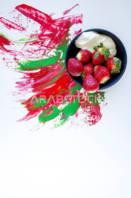 A plate of strawberry and yogurt fruit on a white background colored with red and green, background stained with paint, fresh fruit plate, healthy plate