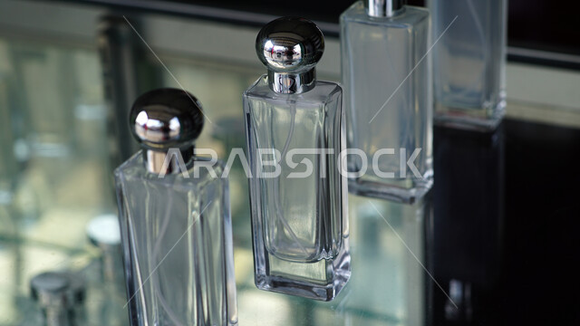 زجاجات عطور شفافة فارغة على طاولة زجاجية، التسويق لمنتجات العطور، التطيب والتعطر