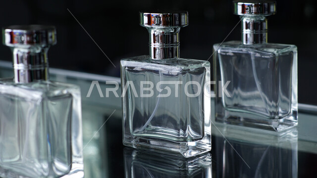 زجاجات عطور شفافة فارغة على طاولة زجاجية، التسويق لمنتجات العطور، التطيب والتعطر