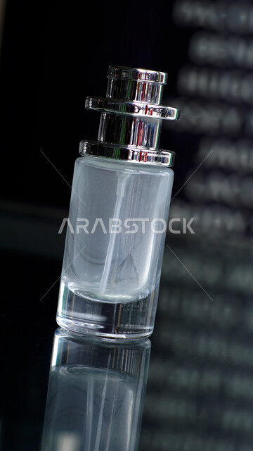 زجاجة عطر اسطوانية الشكل شفافة و فارغة على طاولة زجاجية، التسويق لمنتجات العطور، التطيب والتعطر