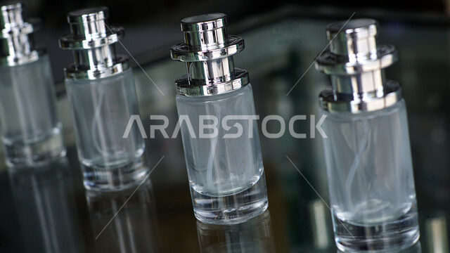 زجاجات عطور شفافة فارغة اسطوانية الشكل على طاولة زجاجية، التسويق لمنتجات العطور، التطيب والتعطر