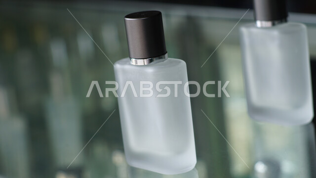 زجاجات عطور شفافة فارغة مستطيلة الشكل على طاولة زجاجية، التسويق لمنتجات العطور، التطيب والتعطر