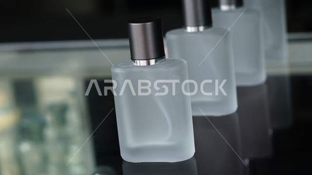 زجاجات عطور شفافة فارغة مستطيلة الشكل على طاولة زجاجية، التسويق لمنتجات العطور، التطيب والتعطر