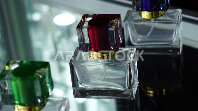 Transparent and empty rectangular perfume bottles with colored caps on a glass table, marketing perfume products, perfuming and perfuming