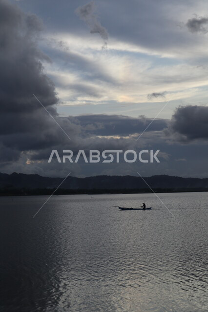 سفينة تبحر وسط البحر وقت غروب الشمس، غيوم كثيفة فوق البحر، هدوء واسترخاء، جمال طبيعة الغيوم والبحار