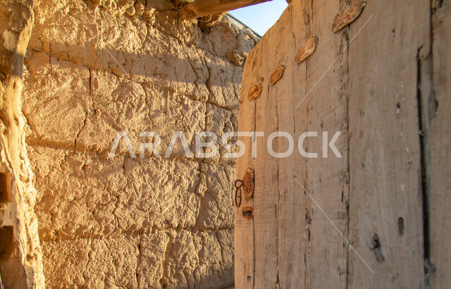 An old open heritage door, historical doors, an old wall, an antique wooden door, archaeological historical places in the Kingdom of Saudi Arabia, old historical houses.