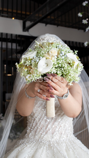 عروس عربية خليجية سعودية تقوم بجلسة تصوير ، مسكة عروس يوم زفافها ، بدلة زفاف بيضاء ، باقة ورود ، ليلة العمر ، مناسبات وأفراح .