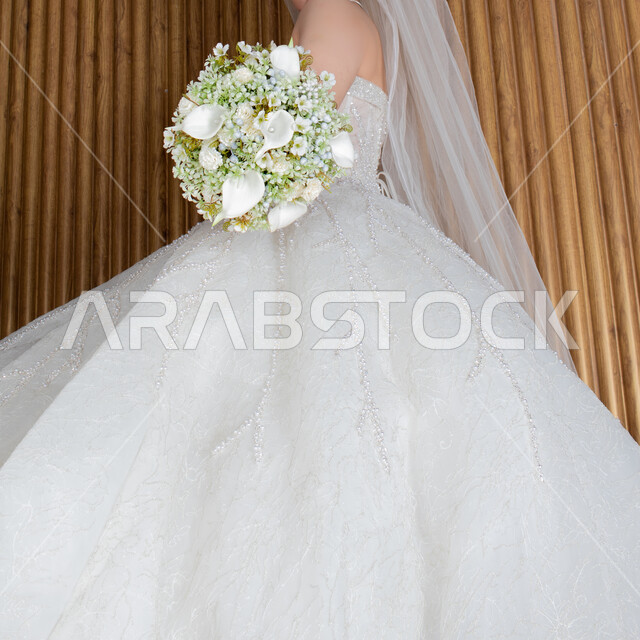 عروس عربية خليجية سعودية تقوم بجلسة تصوير ، مسكة عروس يوم زفافها ، بدلة زفاف بيضاء ، باقة ورود ، ليلة العمر ، مناسبات وأفراح .