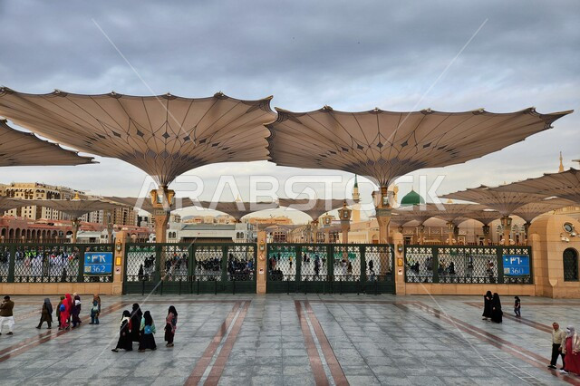 ساحة المسجد النبوي الشريف في المدينة المنورة بالمملكة العربية السعودية، العبادة والتقرب الى الله، الحرم النبوي الشريف، أماكن إسلامية مقدسة، المسلمون يمشون في المجمع الخارجي للمسجد النبوي في المدينة المنورة، المظلات الإلكترونية