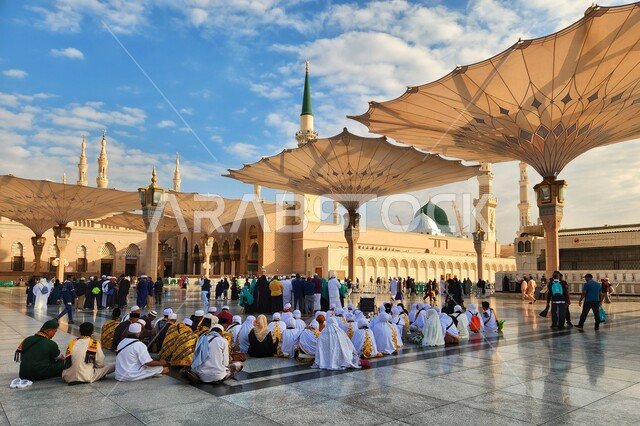 ساحة المسجد النبوي الشريف في المدينة المنورة بالمملكة العربية السعودية، العبادة والتقرب الى الله، الحرم النبوي الشريف، أماكن إسلامية مقدسة، المسلمون يمشون في المجمع الخارجي للمسجد النبوي في المدينة المنورة، المظلات الإلكترونية