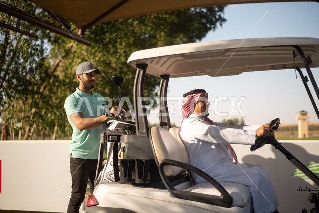 رجلان عربيان خليجيان سعوديان في ملعب الجولف، ممارسة لعبة الغولف على مساحات واسعة خضراء، سيارة كهربائية مختصة بنقل الركاب، أنشطة رياضية بالسعودية، لعبة الجولف، رياضات الألعاب الأولمبية الصيفية، أنشطة ترفيهية