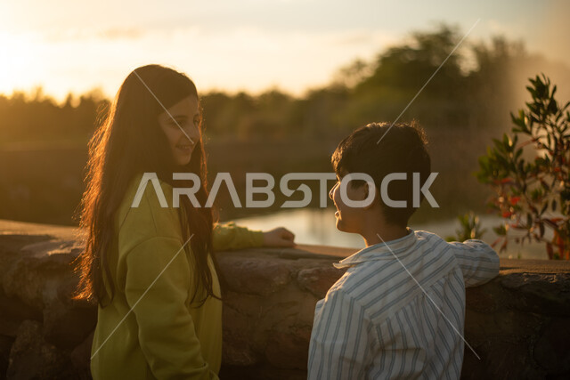 ولد وبنت عربيان خليجيان سعوديان يقضيان أوقات ممتعة، منتجع ترفيهي وقت غروب الشمس، نزهة في الحدائق العامة، جولة في الطبيعة الخضراء، أنشطة ترفيهية، التنزه في الهواء الطلق