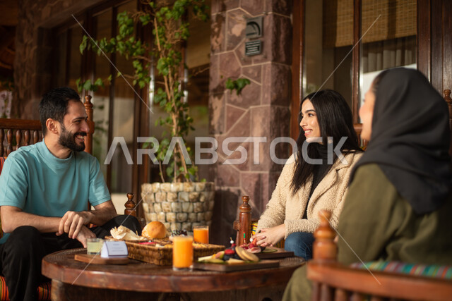 رجل وامرأتان عرب خليجيين سعوديين يتبادلون الحديث في احد المقاهي السعودية، المشروبات الباردة، ديوانية سعودية، نقاشات وحوارات، قضاء أوقات ممتعة، وناسة وتعارف، مقهى سعودي