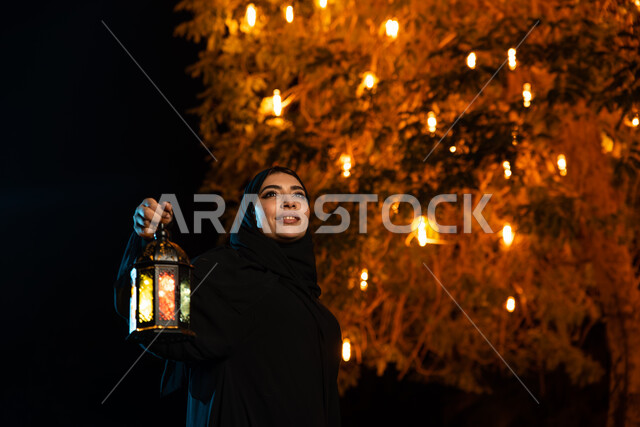 A Saudi Gulf Arab woman holding a Ramadan lantern, lighting and decorations for the month of Ramadan, Ramadan atmosphere, the blessed month of Ramadan, religious occasions
