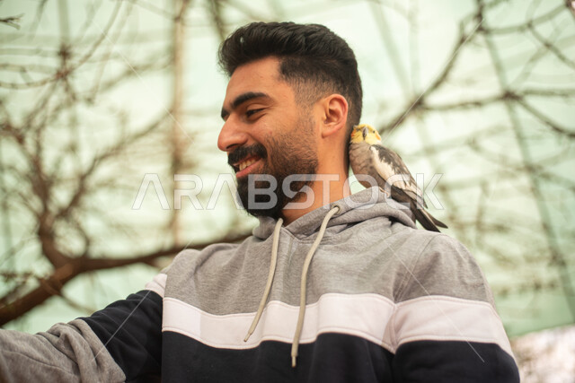 رجل عربي خليجي سعودي يقضي أوقات ممتعة في محمية الطيور في المملكة العربية السعودية ، ايماءات وجه سعيدة ، أنشطة ترفيهية مع الطيور، أماكن سياحية ترفيهية.