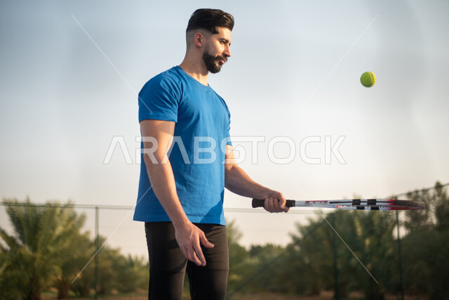شاب عربي خليجي سعودي يمارس كرة التنس الأرضي، لعب كرة المضرب في الملاعب العامة، العاب رياضية، ملعب رياضي، تدريبات رياضية، مضرب رياضي، انشطه ترفيهيه رياضية، انشطة ورياضات شبابية، نشاط بدني