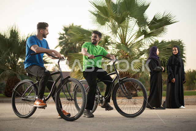 صديقان عربيان خليجيان سعوديان يقودان الدراجة الهوائية في احد الحدائق العامة، ممارسة هواية ركوب الدراجات، أنشطة ترفيهية، عطلة صيفية، أماكن عامة، الحدائق الترفيهية بالسعودية