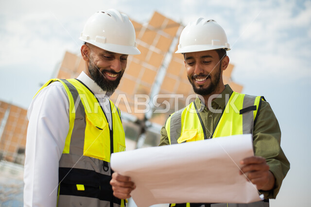 مهندسان طاقة عربيان خليجيان سعوديان يشرفان على محطات الطاقة الشمسية في السعودية، حوارات ونقاشات، إرتداء خوذة وسترة الحماية الخاصة بالعمل، مخططات وتصاميم هندسية، الطاقة المتجددة، الطاقة النظيفة، الطاقة الطبيعية، ستلايت، محطات الطاقة الشمسية