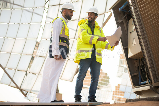 مهندسان طاقة عربيان خليجيان سعوديان يشرفان على محطات الطاقة الشمسية في السعودية، مخططات وتصاميم هندسية، حوارات ونقاشات، إرتداء خوذة وسترة الحماية الخاصة بالعمل، الطاقة المتجددة، الطاقة النظيفة، الطاقة الطبيعية، ستلايت، محطات الطاقة الشمسية