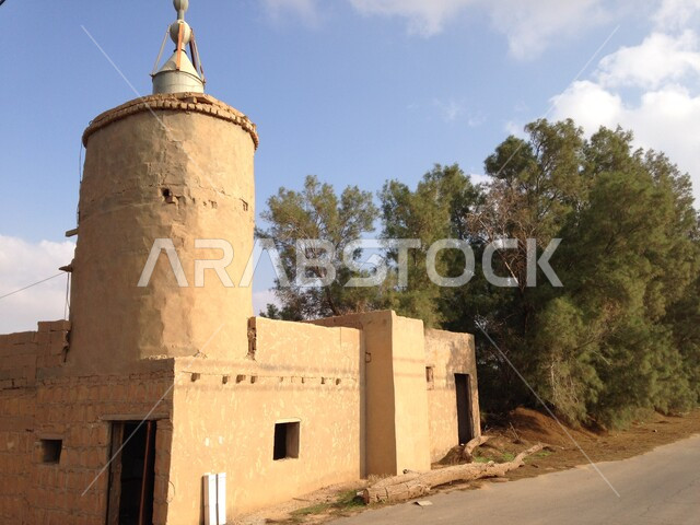 Historic mosque in the Kingdom of Saudi Arabia, an ancient historical mosque, ancient antique designs, the minaret of the mosque, green trees, religious historical landmarks
