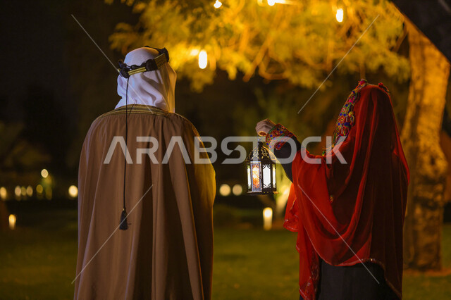 زوجان عربيان سعوديان خليجيان يرتديان زي تراثي شعبي سعودي ويستعدان لقدوم شهر رمضان المبارك، فانوس شهر رمضان، إضاءة وزينة شهر رمضان، ديكورات وأنوار، أجواء رمضانية، مناسبات دينية، زي شعبي سعودي