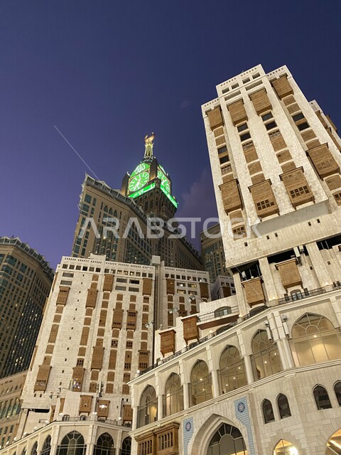 لقطة جانبية من الأسفل لبرج الساعة بين المباني السكنية في مكة المكرمة، بيت الله الحرام، الحرم المكي الشريف، مبنى برج الساعة  بالمسجد الحرام بمكة المكرمة ، المملكة العربية السعودية.