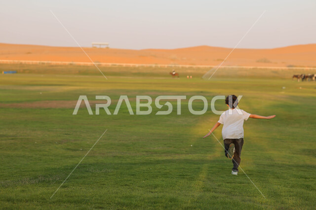 ولد عربي خليجي سعودي يقضي أوقات ممتعة في احد الأماكن الترفيهية السياحية بالمملكة العربية السعودية ، المساحات الواسعة الخضراء ، نادي الفروسية ، أنشطة ترفيهية ، فعالية سفاري موسم الرياض