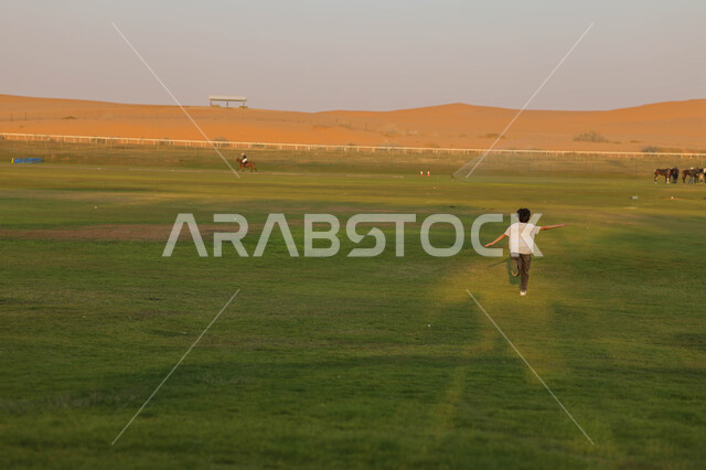ولد عربي خليجي سعودي يقضي أوقات ممتعة في احد الأماكن الترفيهية السياحية بالمملكة العربية السعودية ، المساحات الواسعة الخضراء ، نادي الفروسية ، أنشطة ترفيهية ، فعالية سفاري موسم الرياض