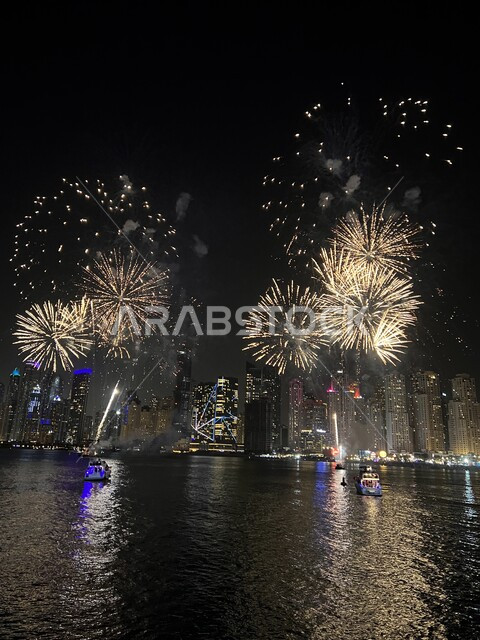 Celebration of fireworks at night, boats in the middle of the sea, celebrations, holidays and events, fireworks activities near buildings and skyscrapers, lighting colorful fireworks at night.