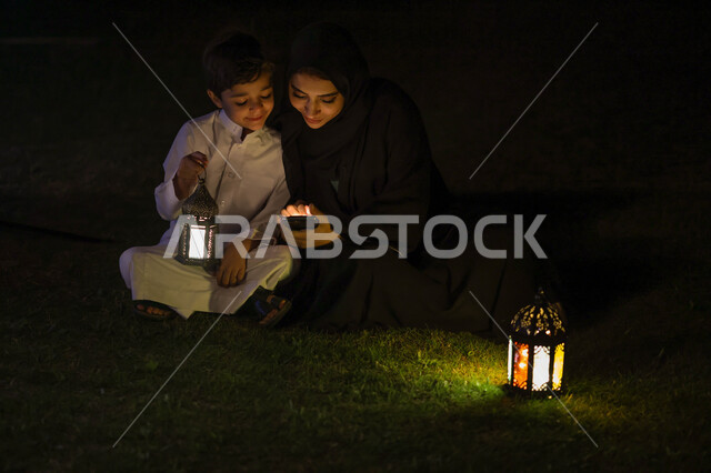 امرأة عربية خليجية سعودية تقضي اوقات ممتعة مع ابنها، استخدام الهاتف المحمول، التواصل الاجتماعي، تصفح المواقع الالكترونية، فانوس رمضان، شهر رمضان المبارك، إضاءة وزينة شهر رمضان، أجواء رمضانية، مناسبات دينية