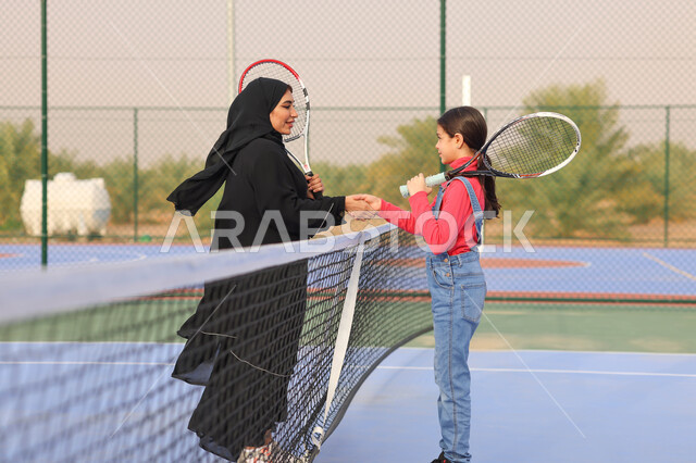 ام عربية خليجية سعودية تقوم بمصافحة ابنتها، لعب كرة المصرب، ممارسة كرة التنس الارضي، الملاعب العامة، ملعب رياضي، انشطة ترفيهية رياضية، العاب رياضية، اللعب والترفيه، قضاء أوقات عائلية ممتعة