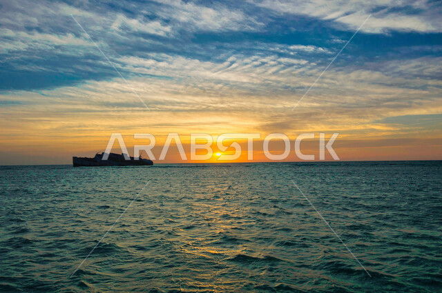 ظل سفينة تبحر في وسط البحر وقت غروب الشمس، هدوء واسترخاء، رحلات بحرية أثناء الغروب، جمال طبيعة أمواج البحر