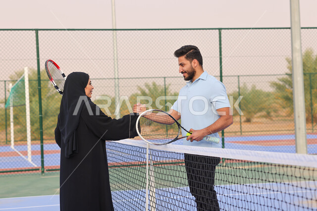 زوجان عربيان خليجيان سعوديان يتصافحان استعدادا لبدء لعب كرة المضرب، قضاء أوقات عائلية ممتعة، ممارسة كرة التنس الارضي، الملاعب العامة، ملعب رياضي، انشطة ترفيهية رياضية، العاب رياضية، اللعب والترفيه 