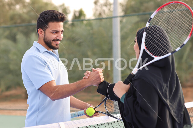 زوجان عربيان خليجيان سعوديان يتصافحان استعدادا لبدء لعب كرة المضرب، قضاء أوقات عائلية ممتعة، ممارسة كرة التنس الارضي، الملاعب العامة، ملعب رياضي، انشطة ترفيهية رياضية، العاب رياضية، اللعب والترفيه 