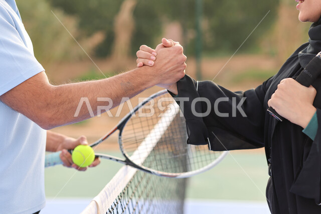 صورة مقربة لزوجان عربيان خليجيان سعوديان يتصافحان استعدادا لبدء لعب كرة المضرب، قضاء أوقات عائلية ممتعة، ممارسة كرة التنس الارضي، الملاعب العامة، ملعب رياضي، انشطة ترفيهية رياضية، العاب رياضية، اللعب والترفيه 