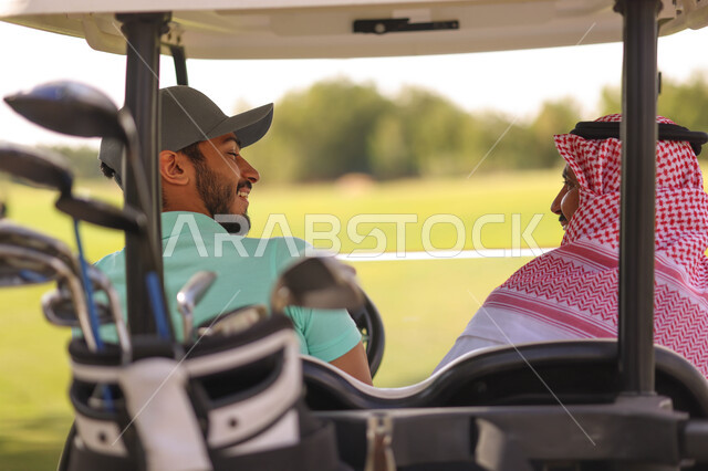 زاوية من الخلف لرجلان عربيان خليجيان سعوديان داخل سيارة كهربائية مختصة بنقل الركاب، لعبة الغولف ( الجولف ) ، أنشطة رياضية بالسعودية، رياضات الألعاب الأولمبية الصيفية، أنشطة ترفيهية، ملعب الجولف، نادي الجولف