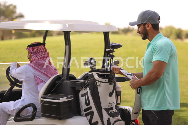 رجلان عربيان خليجيان سعوديان في ملعب الجولف، سيارة كهربائية مختصة بنقل الركاب، ممارسة لعبة الغولف على مساحات واسعة خضراء، أنشطة رياضية بالسعودية، لعبة الجولف، رياضات الألعاب الأولمبية الصيفية، أنشطة ترفيهية